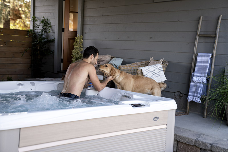 Man petting dog from inside a best Caldera salt water hot tub